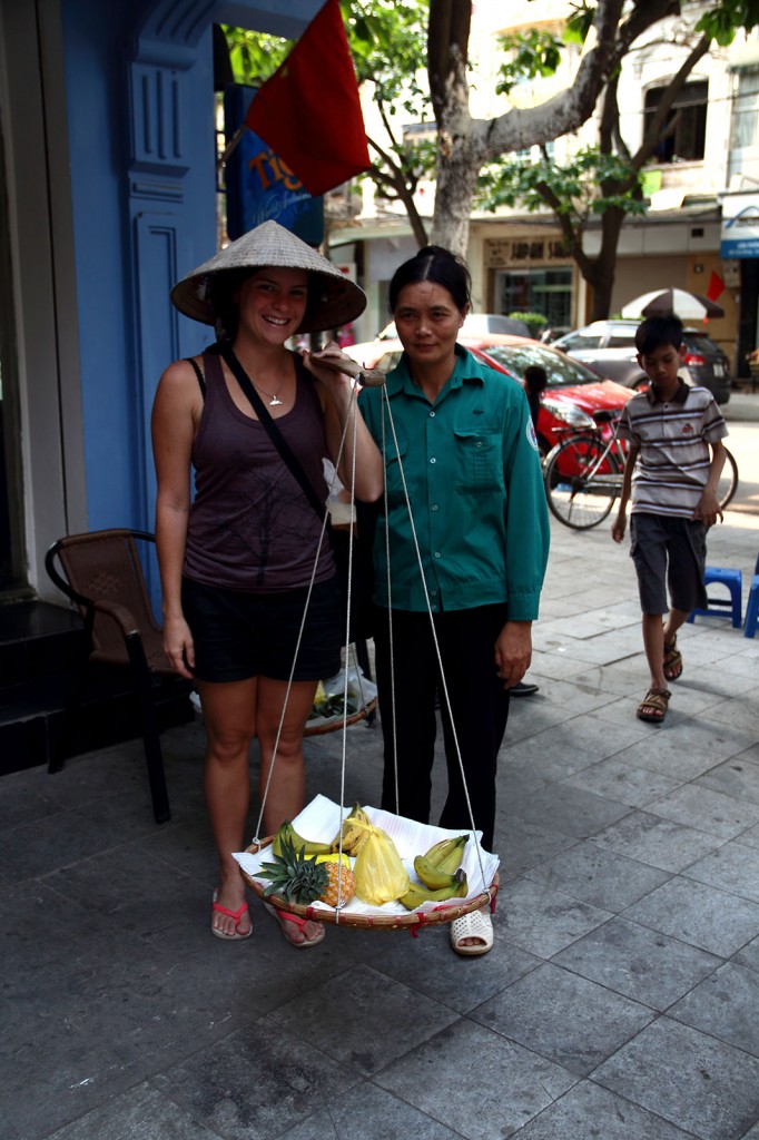 Kris carregando frutas nas ruas de Hanoi